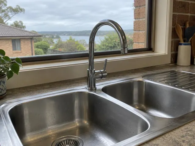 Chrome kitchen mixer tap over a stainless steel double sink beneath a window in Swan Bay